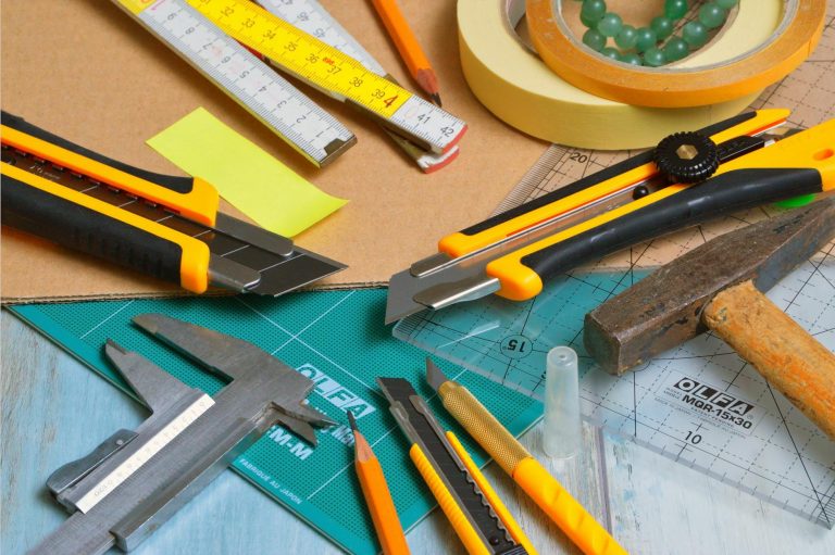 Werkzeuge mit C – Cuttermesser und Schneidwerkzeuge auf Arbeitstisch