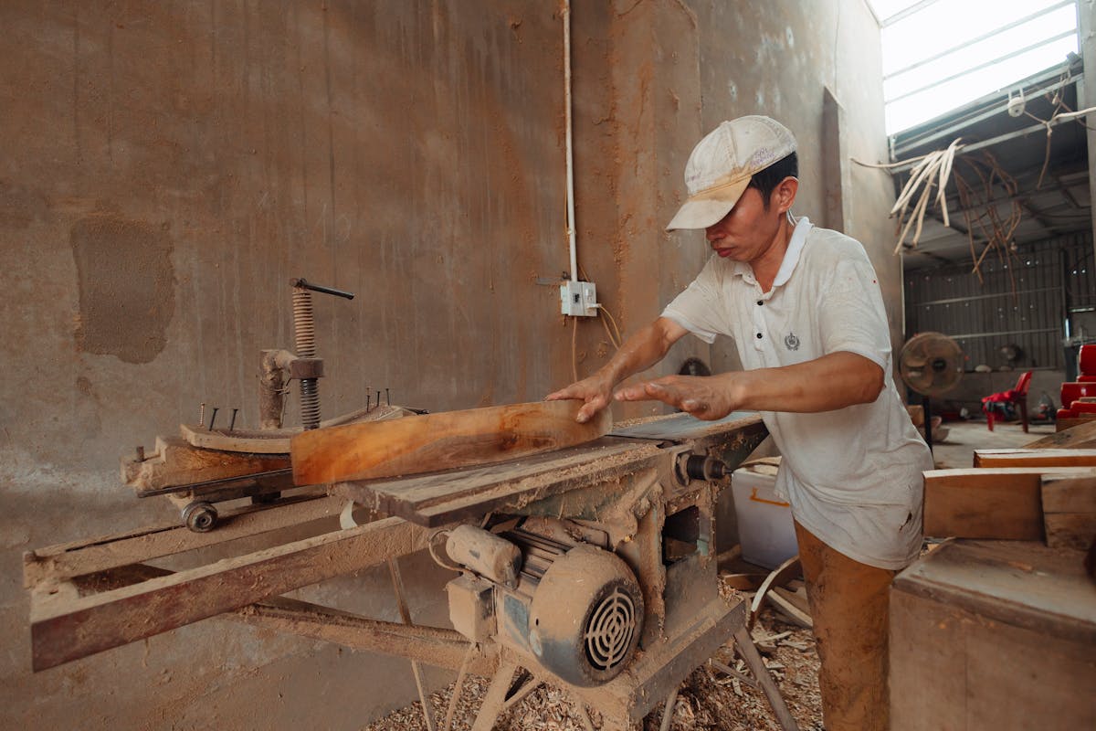 Werkzeuge mit S – Zimmermann sägt Holz mit Industriesäge in der Werkstatt