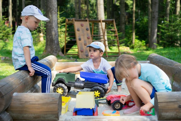Sandkasten selber bauen: Anleitung, Maße und kindersicheres Holz Sandkasten selber bauen – Kinder spielen in einem Sandkasten aus Holz