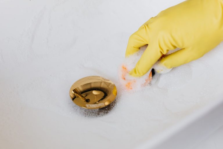 Waschbecken verstopft – Abfluss wird mit Handschuhen gereinigt