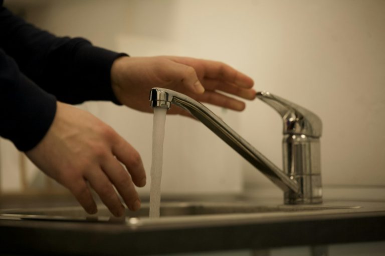Wasserhahn aufdrehen: In welche Richtung er aufgeht Wasserhahn aufdrehen – Hand öffnet einen Einhebelmischer, Wasser läuft