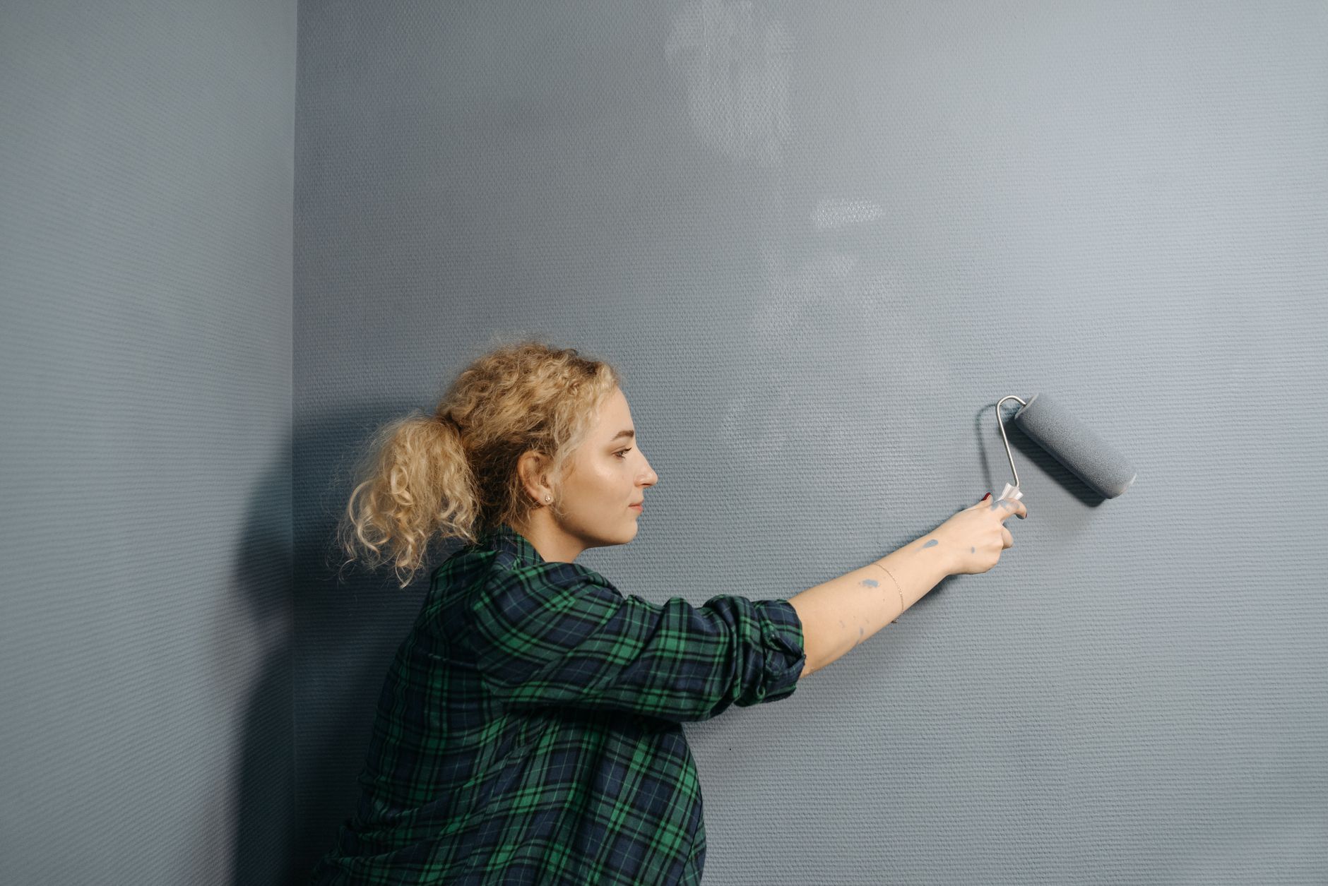 Silikatfarbe streichen – Person rollt Wandfarbe gleichmäßig auf eine Wand