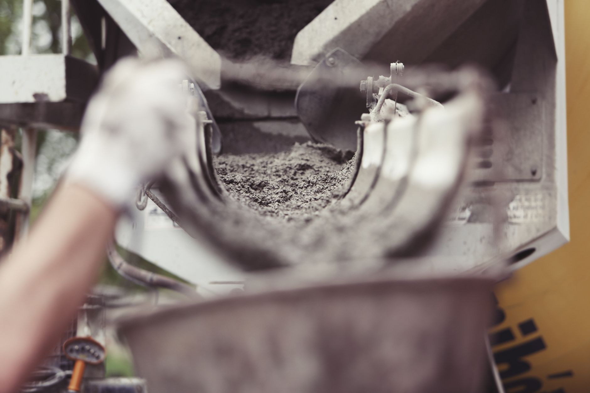 Beton mischen – Hände rühren frischen Beton im Mischer an