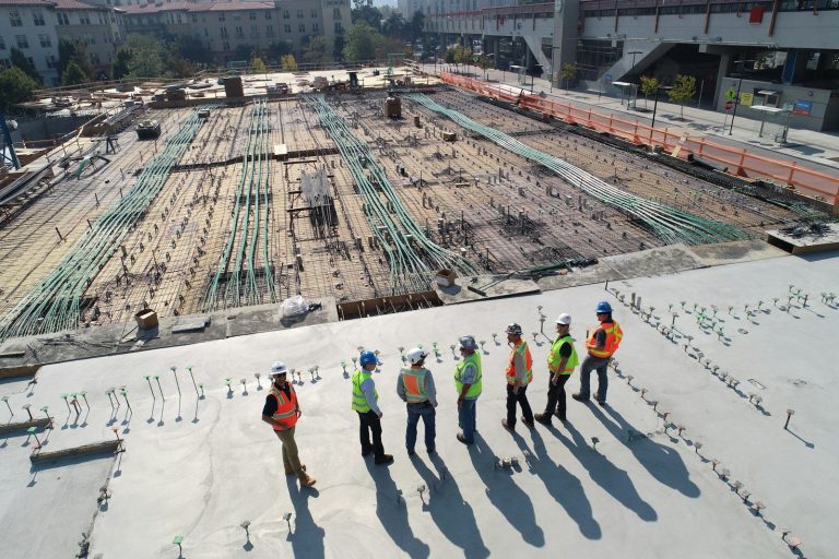 Ladungssicherung auf der Baustelle: Material richtig bündeln und transportieren seven construction workers standing on white field
